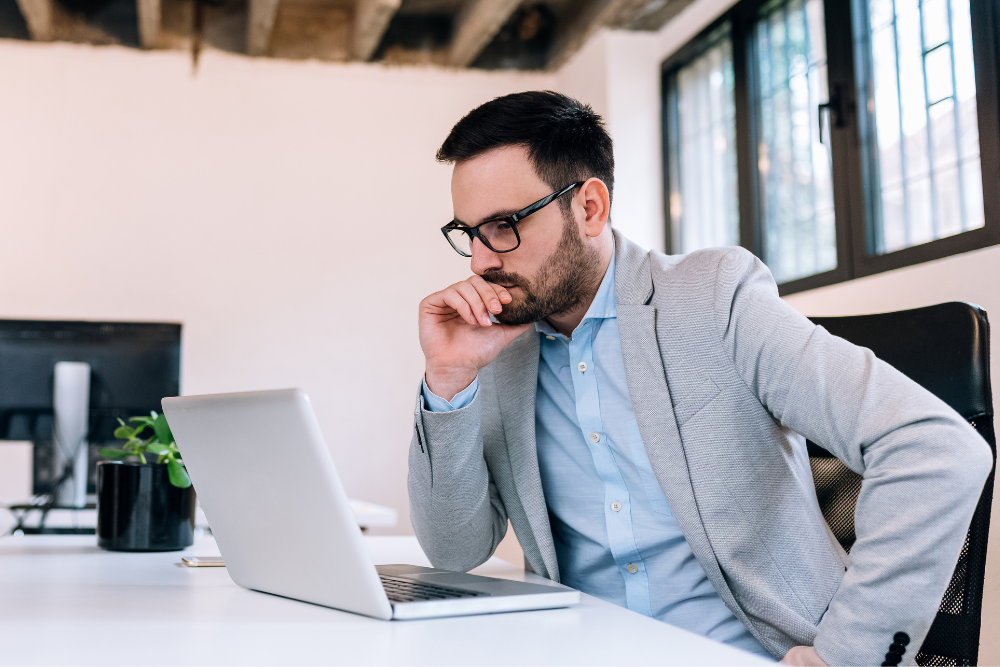 A business man listens to the Cloud and Clear podcast on a laptop. 